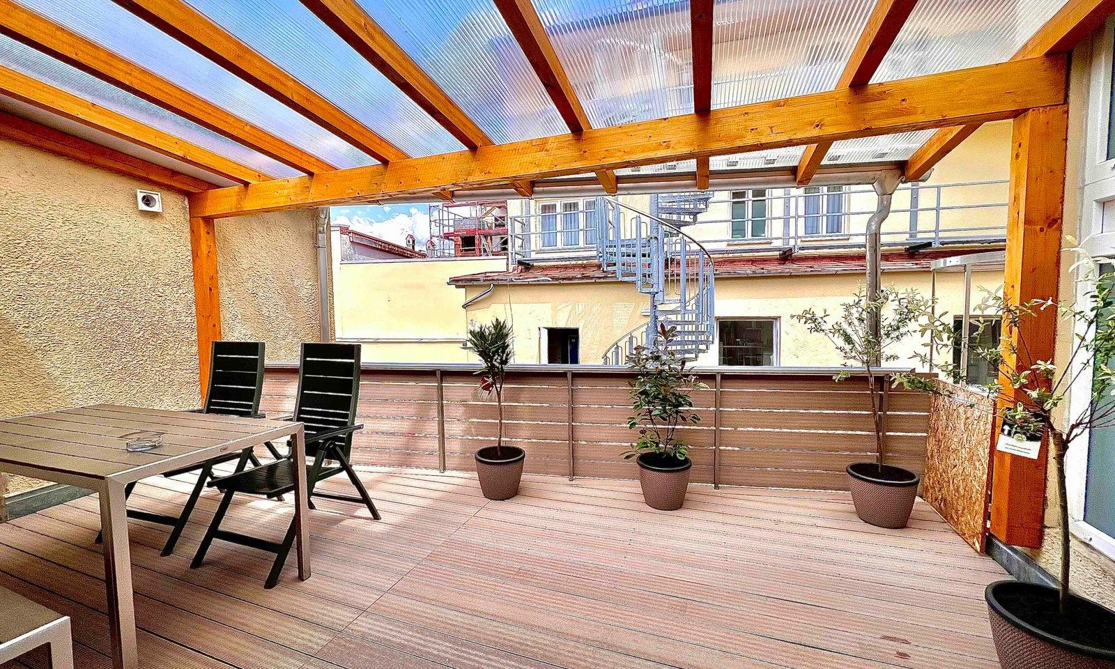 Überdachte Terrasse mit Tischen, Stühlen und Pflanzen