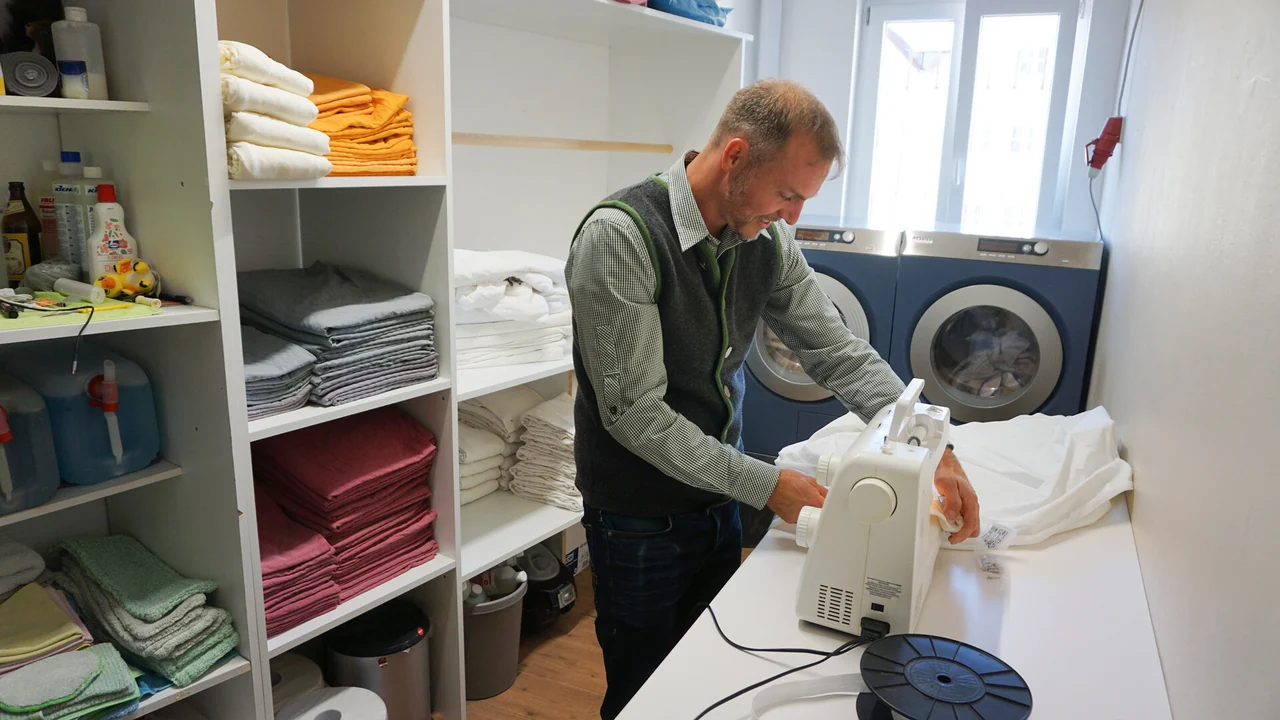 Dominik Ostheimer näht an der Nähmaschine Bezüge für die Gästebetten