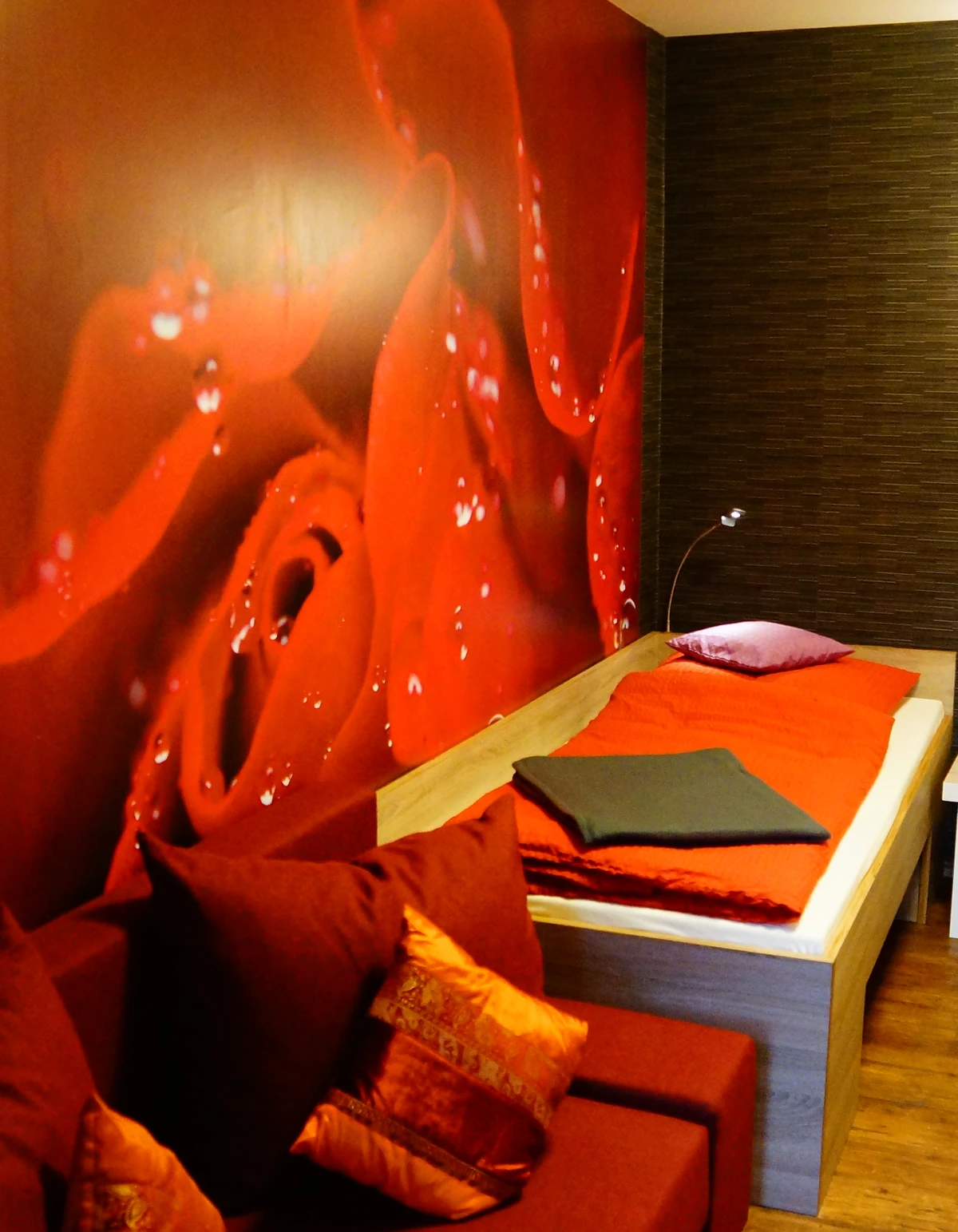 Das Zimmer Rosegarden mit roter Rosenwand, Bett und Sofa